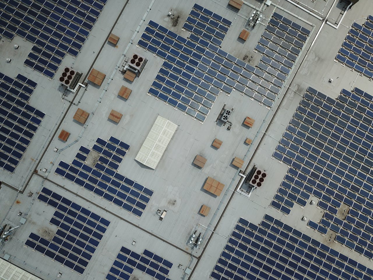 Home High-angle aerial shot of a large rooftop solar panel array on an industrial building.