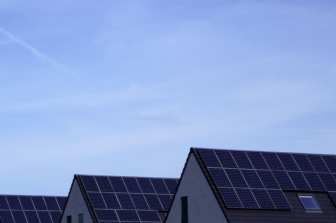 Modern Belgian houses with solar panels on rooftops under a clear blue sky.